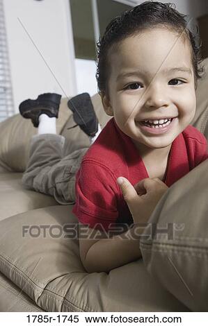 Portrait of a boy lying on a sofa View Large Photo Image Stock Photography - Portrait of a boy lying on a sofa. Fotosearch