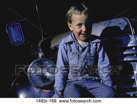 Stock Photo - Portrait of a boy sitting on the front of a car smiling. Fotosearch