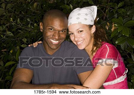 Picture - Portrait of a cheerful young multi-ethnic couple smiling and embracing. Fotosearch