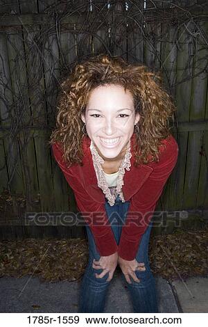 Portrait of a cheerful young woman with wooden fence in background View Large Photo Image Stock Photo - Portrait of a cheerful young woman with wooden fence in background. Fotosearch