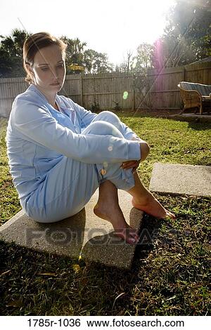 Stock Photograph - Portrait of a contemplative young woman sitting on a stepping stone. Fotosearch