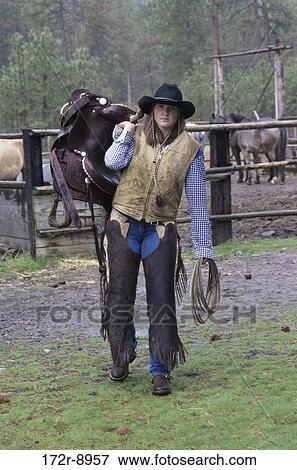 Portrait of a cowgirl holding a saddle View Large Photo Image Stock Photo - Portrait of a cowgirl holding a saddle. Fotosearch