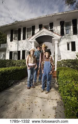 Stock Image - Portrait of a family in country clothes standing in front of a house. Fotosearch