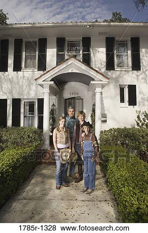 Stock Photo - Portrait of a family in country clothes standing in front of a house. Fotosearch