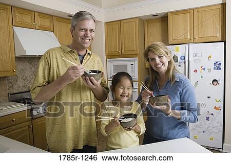 Portrait of a family in kitchen holding bowls of rice and chopsticks View Large Photo Image Stock Photograph - Portrait of a family in kitchen holding bowls of rice and chopsticks. Fotosearch