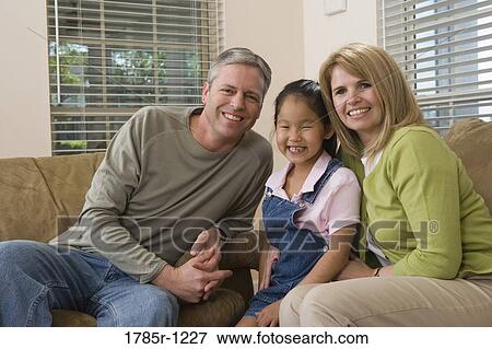 Stock Photo - Portrait of a family sitting in living room. Fotosearch