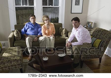 Stock Image - Portrait of a family sitting on a sofa at home. Fotosearch