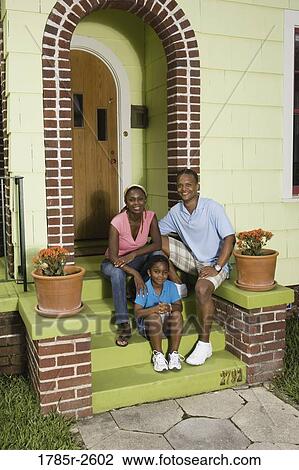 Stock Image - Portrait of a family sitting on front steps of house. Fotosearch