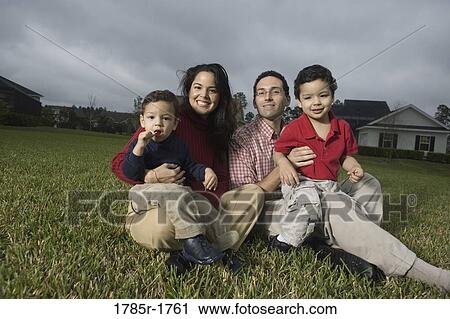 Stock Image - Portrait of a family sitting on lawn. Fotosearch