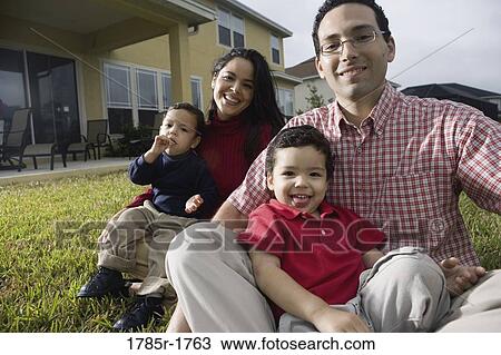Stock Image - Portrait of a family sitting on lawn. Fotosearch