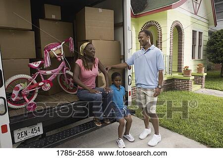 Stock Photo - Portrait of a family standing outside a house by moving truck. Fotosearch