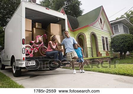Stock Photo - Portrait of a family standing outside a house by moving truck. Fotosearch