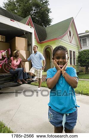 Stock Photograph - Portrait of a family standing outside a house by moving truck. Fotosearch