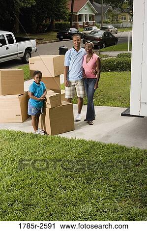 Stock Image - Portrait of a family standing with cartons in driveway. Fotosearch