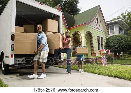 Stock Photograph - Portrait of a family unloading boxes from moving truck. Fotosearch