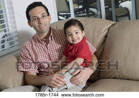 Portrait of a father sitting with his son on a sofa View Large Photo Image Picture - Portrait of a father sitting with his son on a sofa. Fotosearch