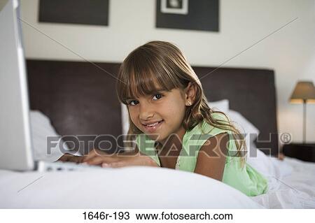 Portrait of a girl lying in the bed and using a laptop View Large Photo Image Stock Image - Portrait of a girl lying in the bed and using a laptop. Fotosearch