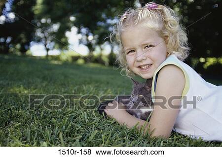 Portrait of a girl lying on grass with her kitten View Large Photo Image Stock Photo - Portrait of a girl lying on grass with her kitten. Fotosearch