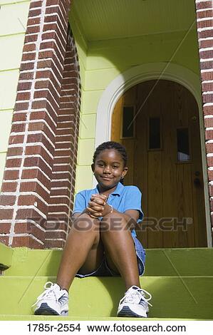 Picture - Portrait of a girl sitting on front steps of house. Fotosearch