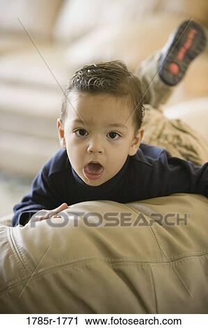Stock Image - Portrait of a little boy lying on a sofa. Fotosearch