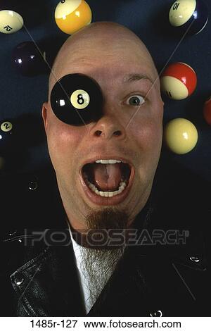 Stock Photo - Portrait of a man surrounded by pool balls with the eight ball on his eye. Fotosearch