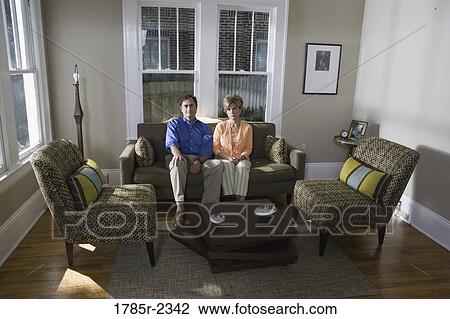 Stock Image - Portrait of a mature couple sitting on a sofa at home. Fotosearch