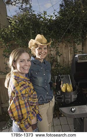 Stock Image - Portrait of a mother and a daughter standing near barbeque grill. Fotosearch