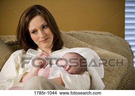 Portrait of a mother feeding an infant with a feeding bottle View Large Photo Image Picture - Portrait of a mother feeding an infant with a feeding bottle. Fotosearch