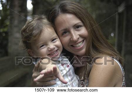 Stock Photo - Portrait of a mother holding her baby girl smiling. Fotosearch