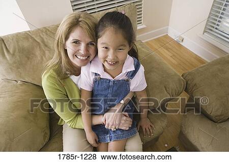 Portrait of a mother with her daughter sitting on sofa View Large Photo Image Stock Photo - Portrait of a mother with her daughter sitting on sofa. Fotosearch