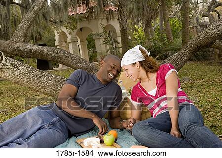 Portrait of a romantic young couple lying on a picnic blanket under oak trees View Large Photo Image Picture - Portrait of a romantic young couple lying on a picnic blanket under oak trees. Fotosearch