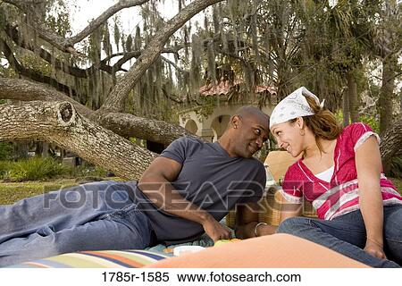 Portrait of a romantic young couple lying on a picnic blanket under oak trees View Large Photo Image Stock Photography - Portrait of a romantic young couple lying on a picnic blanket under oak trees. Fotosearch