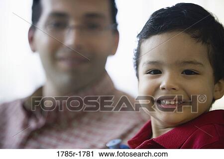 Stock Image - Portrait of a smiling little boy with his father in the background. Fotosearch