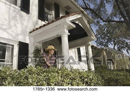 Portrait of a woman tending plants outside house View Large Photo Image Stock Photograph - Portrait of a woman tending plants outside house. Fotosearch