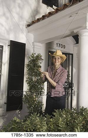 Portrait of a woman tending plants outside house View Large Photo Image Stock Photography - Portrait of a woman tending plants outside house. Fotosearch