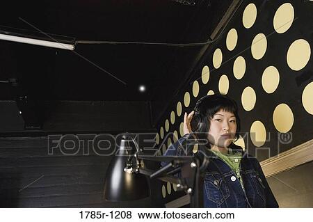 Stock Photo - Portrait of a young Asian woman listening to music. Fotosearch