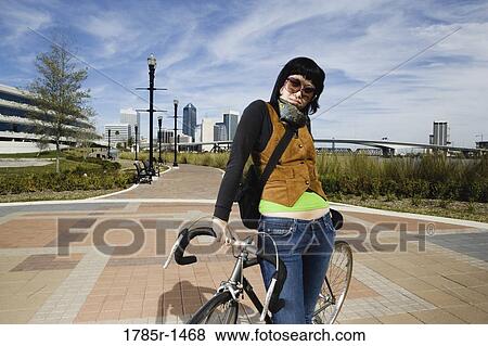 Portrait of a young Asian woman standing with her bicycle View Large Photo Image Stock Photo - Portrait of a young Asian woman standing with her bicycle. Fotosearch