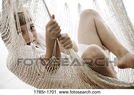 Stock Image - Portrait of a young boy sitting in a hammock. Fotosearch