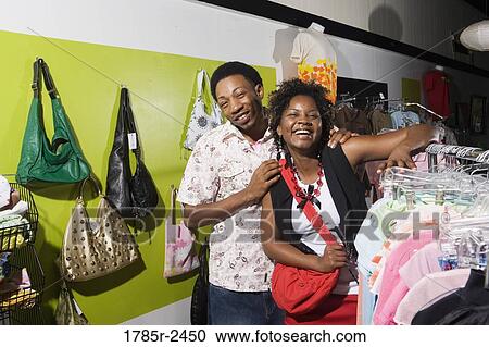 Stock Image - Portrait of a young couple shopping for women's clothes in a boutique. Fotosearch