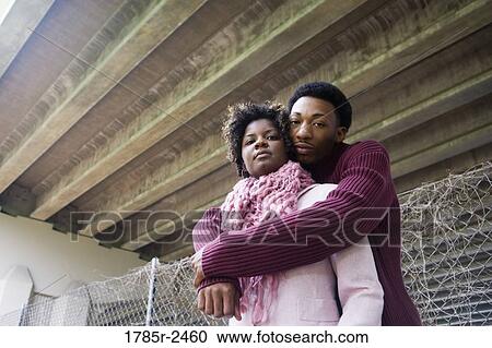 Stock Image - Portrait of a young couple standing under a highway overpass. Fotosearch