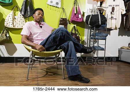 Portrait of a young man sitting in a boutique View Large Photo Image Picture - Portrait of a young man sitting in a boutique. Fotosearch