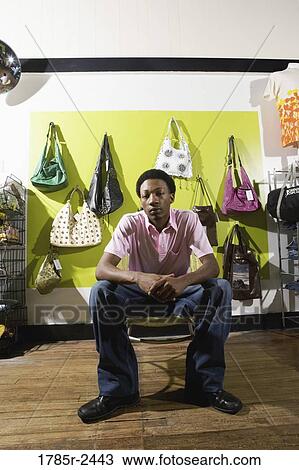 Portrait of a young man sitting in a boutique View Large Photo Image Stock Image - Portrait of a young man sitting in a boutique. Fotosearch