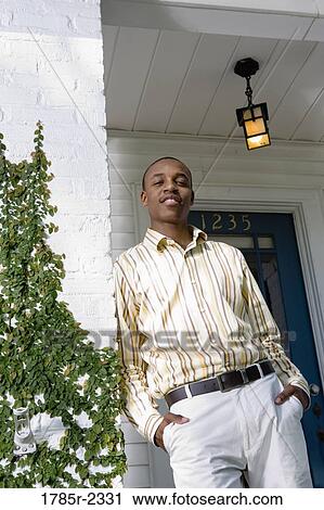 Portrait of a young man standing outside a house View Large Photo Image Stock Image - Portrait of a young man standing outside a house. Fotosearch