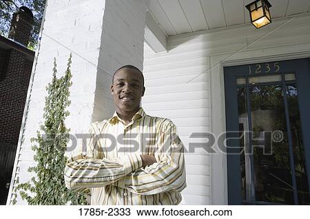 Portrait of a young man standing outside a house View Large Photo Image Stock Image - Portrait of a young man standing outside a house. Fotosearch