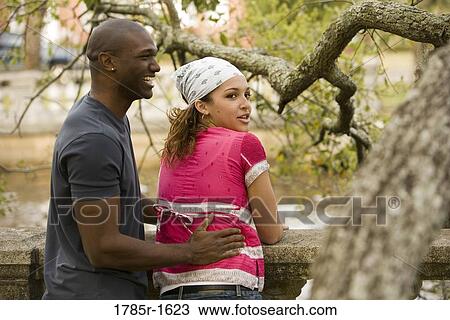 Portrait of a young multi-ethnic couple standing by canal View Large Photo Image Stock Image - Portrait of a young multi-ethnic couple standing by canal. Fotosearch