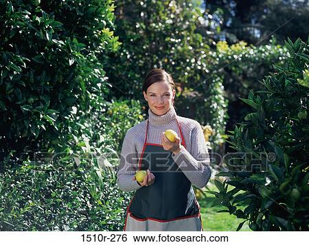 Stock Photograph - Portrait of a young woman holding fruit. Fotosearch