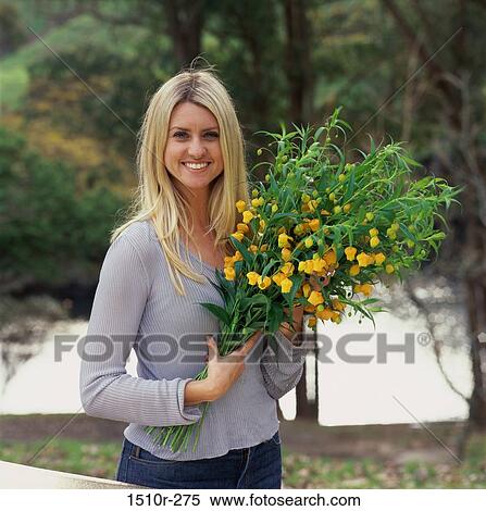 Portrait of a young woman holding flowers View Large Photo Image Stock Photography - Portrait of a young woman holding flowers. Fotosearch