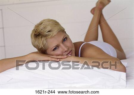 Picture - Portrait of a young woman lying on the bed. Fotosearch