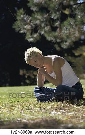 Portrait of a young woman sitting on a lawn View Large Photo Image Stock Image - Portrait of a young woman sitting on a lawn. Fotosearch