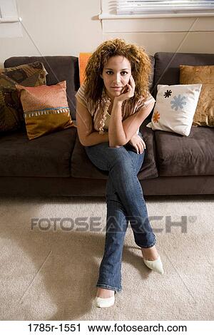 Portrait of a young woman sitting on sofa View Large Photo Image Stock Image - Portrait of a young woman sitting on sofa. Fotosearch